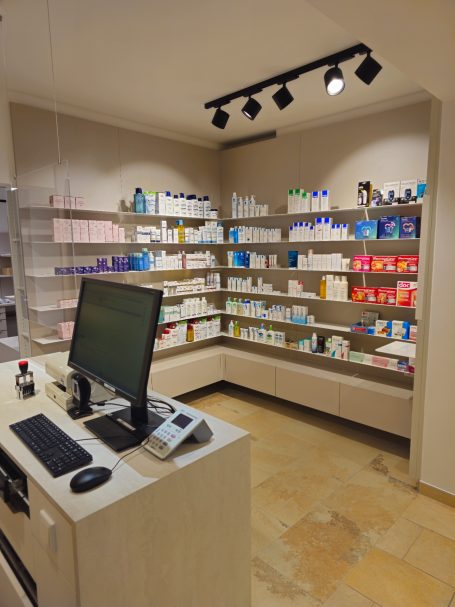 Innenansicht einer modernen Apotheke mit Regalen voller Produkte und einem Empfangstresen.