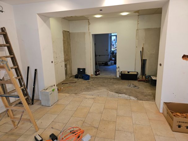 Rohbau eines Raums mit unvollendeten Wänden, Fliesen und Werkzeugen.