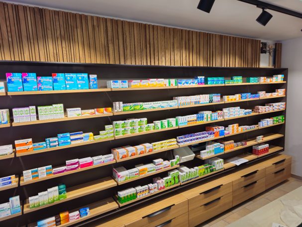 Regal mit verschiedenen Medikamenten und Produkten in einer Apotheke.