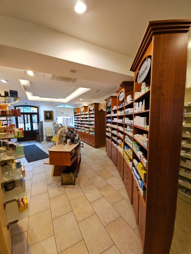 Innenansicht einer Apotheke mit Regalen voller Medikamente und einem Empfangstresen.