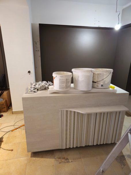 Ein heller Empfangstresen mit Farbeimern und Kabeln in einem unfertigen Raum.