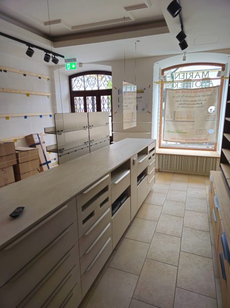 Heller, moderner Verkaufsraum mit Holzregalen und Fenster zur Straßenseite.