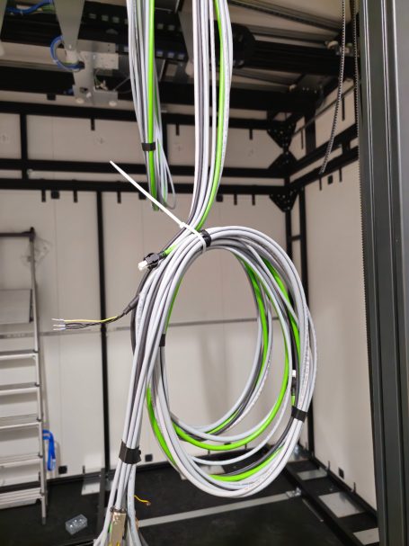 Mehrere weiße und grüne Kabel hängen in einem technischen Raum.