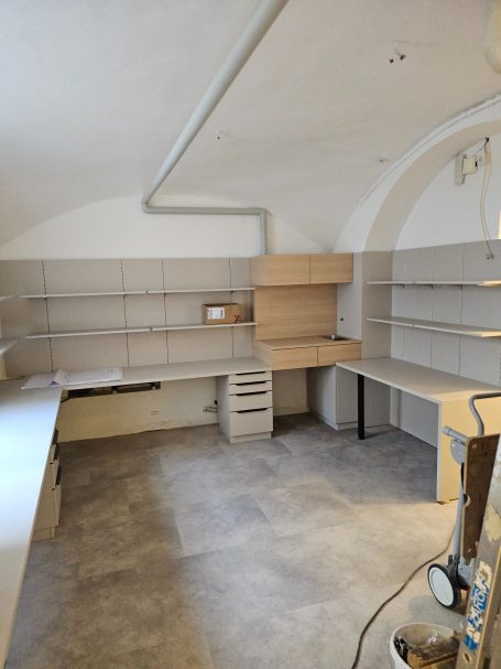 Küchenbereich mit hellen Wänden, Regalen und Arbeitsflächen, modern und unvollständig.