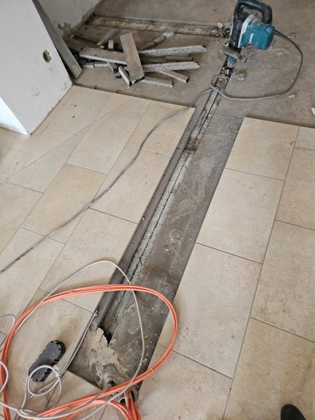 Ein Boden mit einem langen Schnitt, umgeben von Werkzeugen und Kabeln.