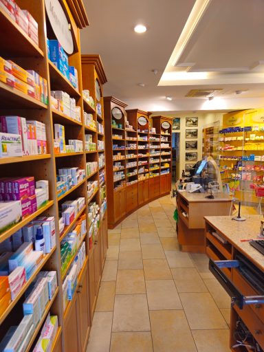 Innenansicht einer Apotheke mit Regalen voller Medikamente und einem Kassentisch.