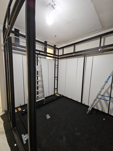 Leerer Raum mit einer strukturierten Wand und einer Leiter im Hintergrund.